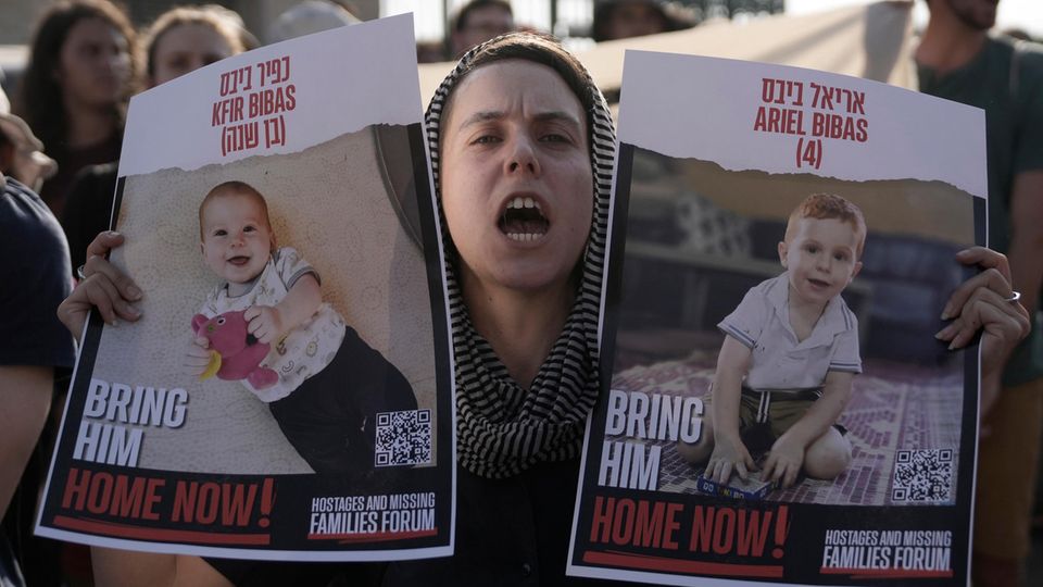 Demonstrantin mit den Plakaten der israelischen Geiseln Kfir und Ariel Bibas