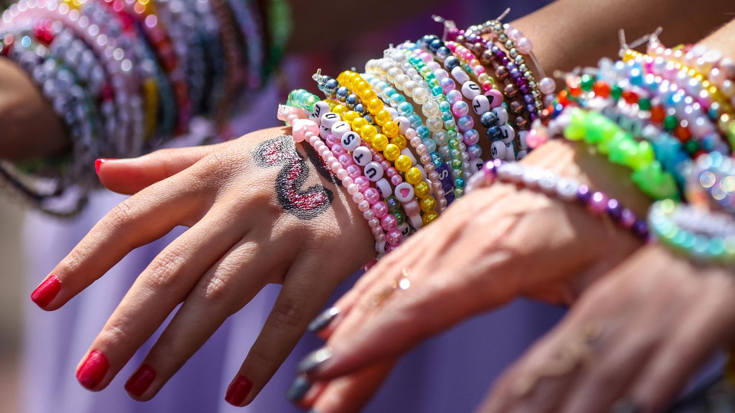 Um die Handgelenke zweier Taylor-Swift-Fans sind etliche Freundschaftsarmbänder gebunden Um die Handgelenke zweier Taylor-Swift-Fans sind etliche Freundschaftsarmbänder gebunden