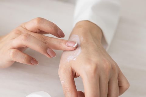 Eine Frau schmiert sich Handcreme auf eine Hand