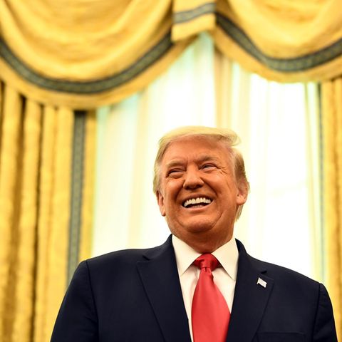 Vor einem Fenster mit schweren goldenen Vorhängen steht US-Präsident Donald Trump und lacht. Wegen des Tiktok-Banns?