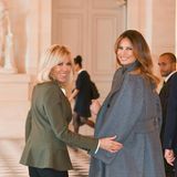 Brigitte Macron und Melania Trump blicken für die Kameras über ihre Schultern