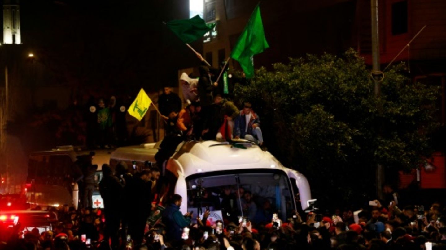Männer mit Hamas- und Hisbollah-Flaggen auf Bus mit Gefangenen