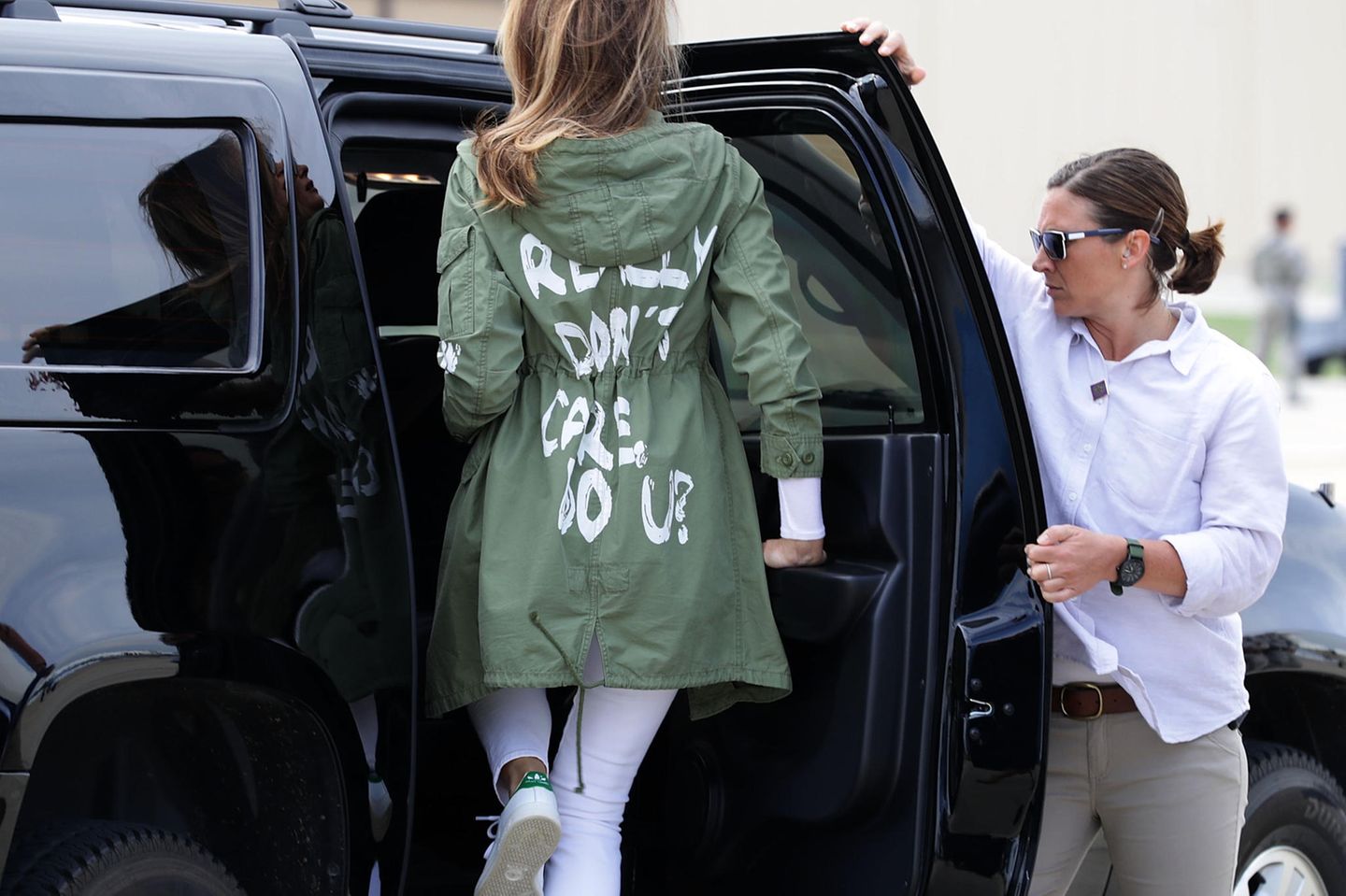 Melania Trump steigt bekleidet in einen grünen Zara Anorak mit dem Aufdruck "I really don't care. Do u?"in einen SUV