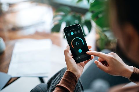 Ein Mann stellt seine Heizung per Smartphone ein