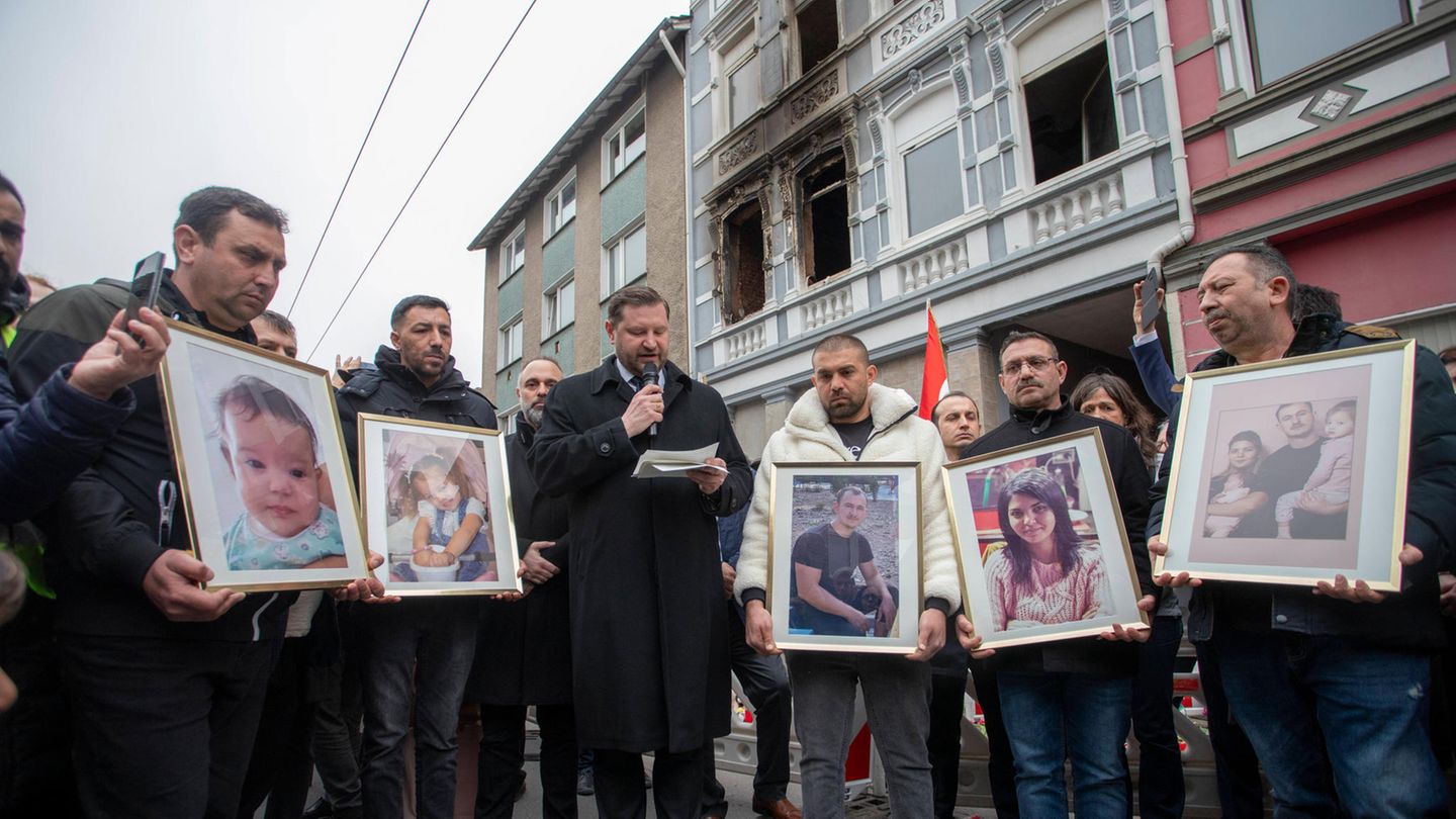 Opferangehörige in Solingen Opferangehörige halten bei einer Gedenkveranstaltung vor dem Brandhaus Fotos der Verstorbenen hoch