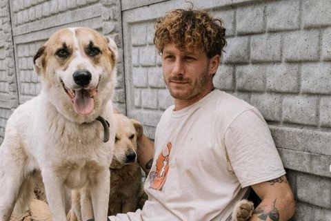 Malte Zierden sitzt mit Hunden auf dem Boden.