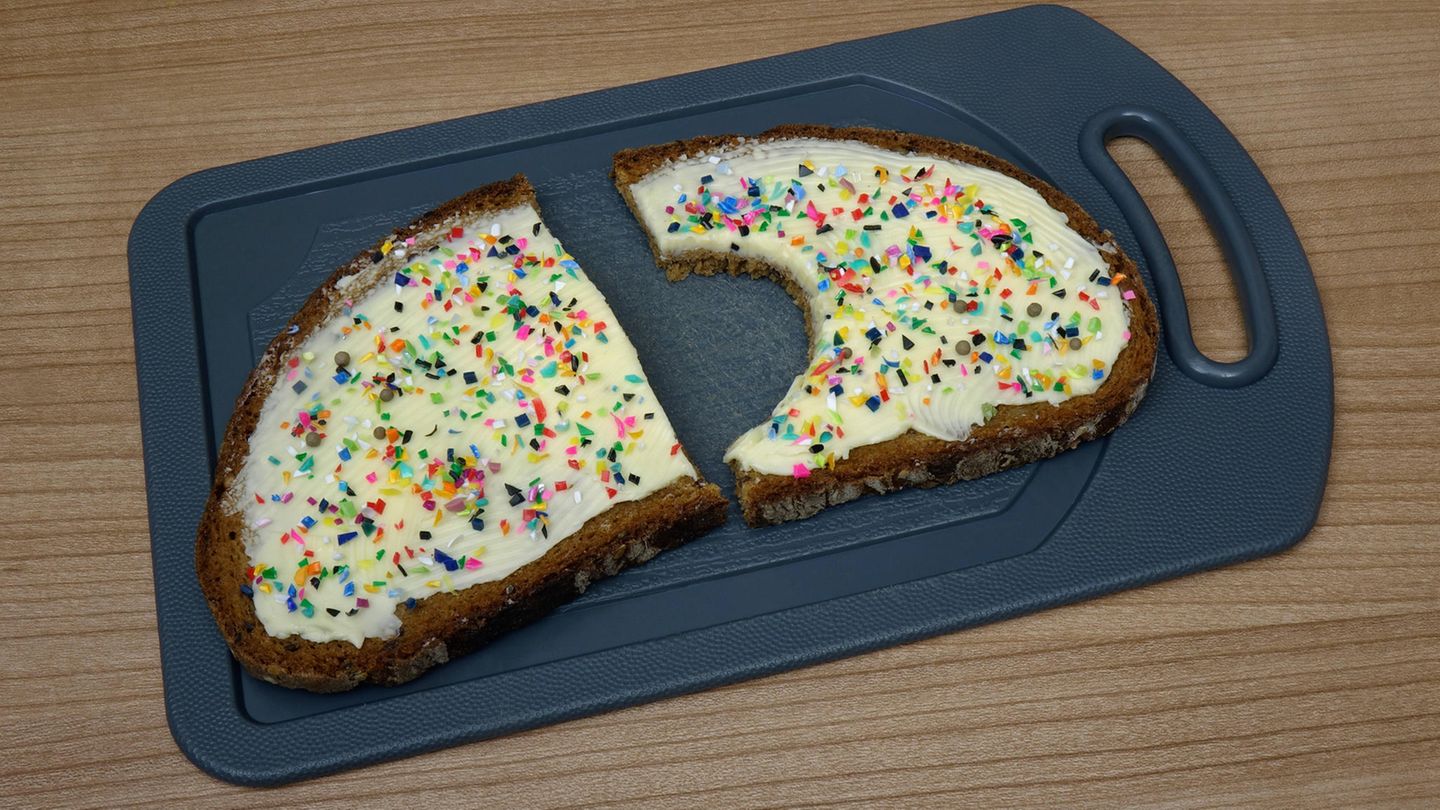 Mikroplastik: angebissene Brotscheibe mit bunten Plastikstückchen Mikroplastik: angebissene Brotscheibe mit bunten Plastikstückchen
