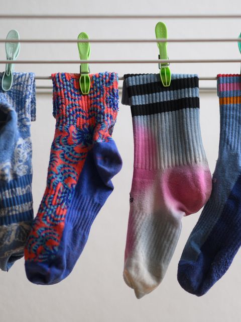 In einer Nahaufnahmen hängen vier bunte Socken auf einem Wäschestände und sind mit Wäscheklammern befestigt