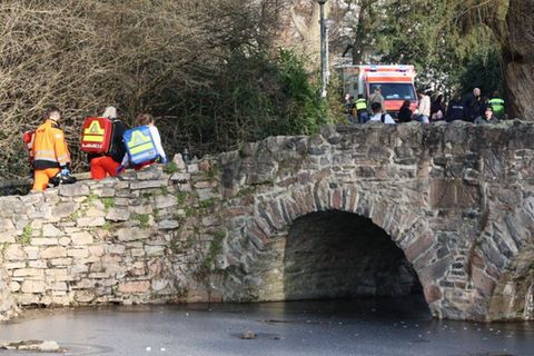 Notfallsanitäter gehen über eine Brücke in einen Park in Aschaffenburg