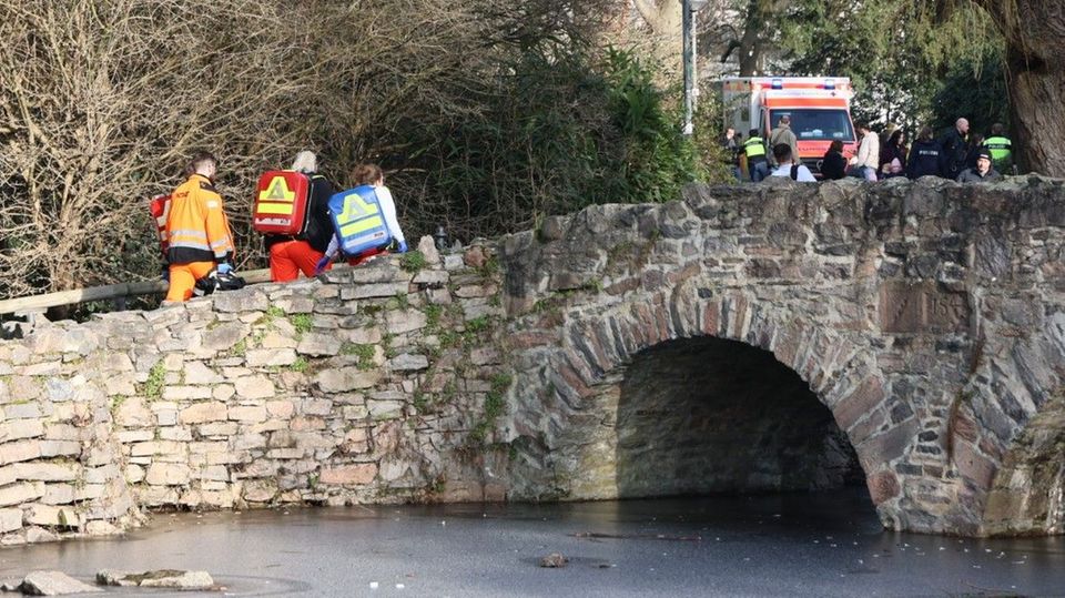 Notfallsanitäter gehen über eine Brücke in einen Park in Aschaffenburg
