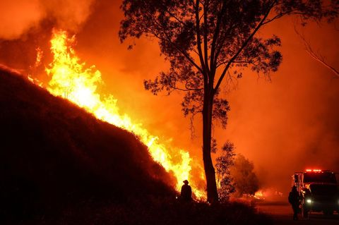 Ein Feuerwehrmann mit einer Flämmkanne beobachtet das Hughes-Feuer, das in der Nähe von Los Angeles entlang eines Hangs brennt