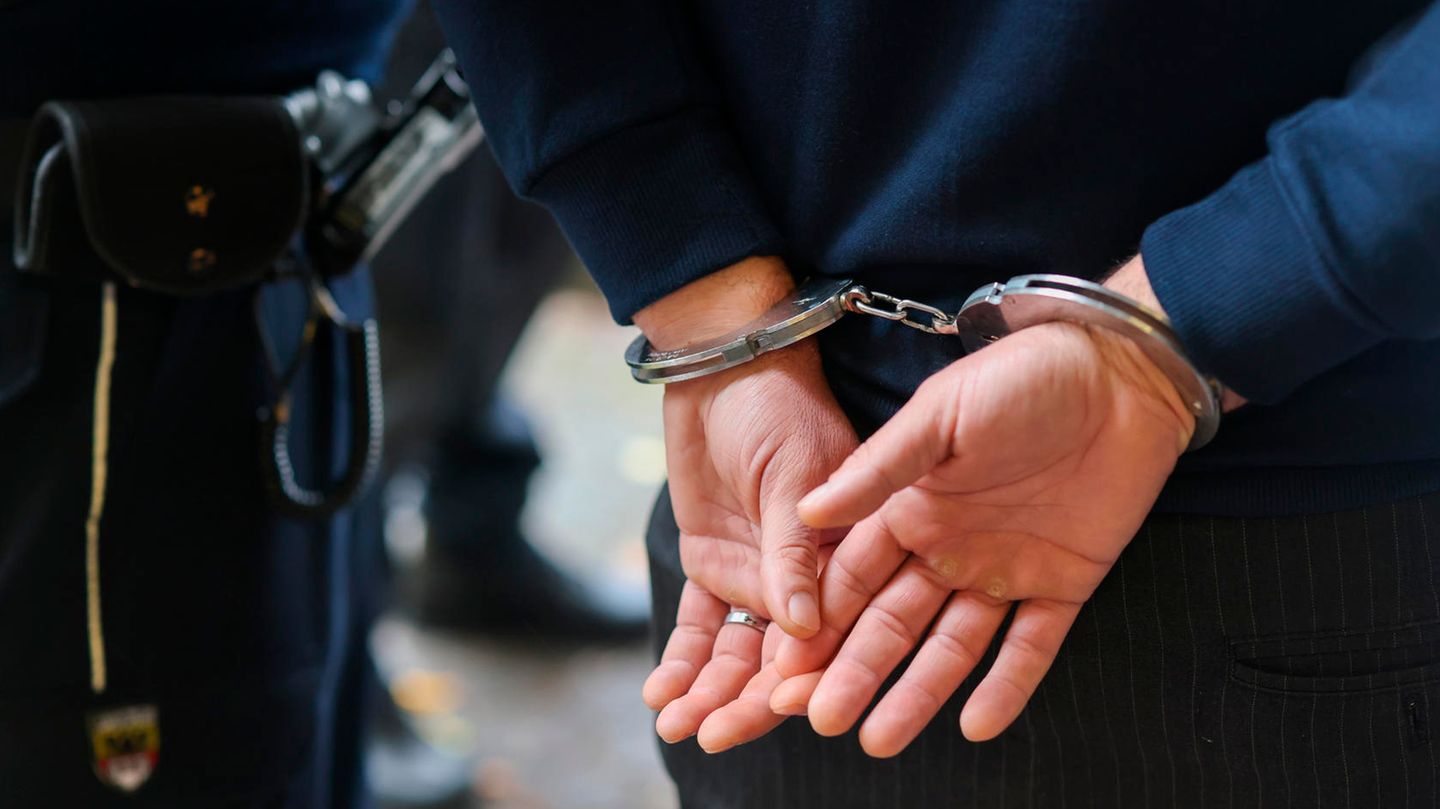 In Nordrhein-Westfalen führt ein Polizist einen Mann in Handschellen ab