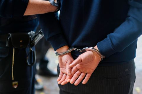 In Nordrhein-Westfalen führt ein Polizist einen Mann in Handschellen ab