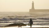 Diese Frau genießt am Strand von Tynemouth an Englands Ostküste die letzten Sonnenstrahlen mit ihrem Vierbeiner, bevor Éowyn das Meer noch weiter aufpeitscht