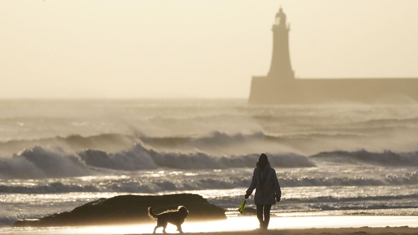 Diese Frau genießt am Strand von Tynemouth an Englands Ostküste die letzten Sonnenstrahlen mit ihrem Vierbeiner, bevor Éowyn das Meer noch weiter aufpeitscht
