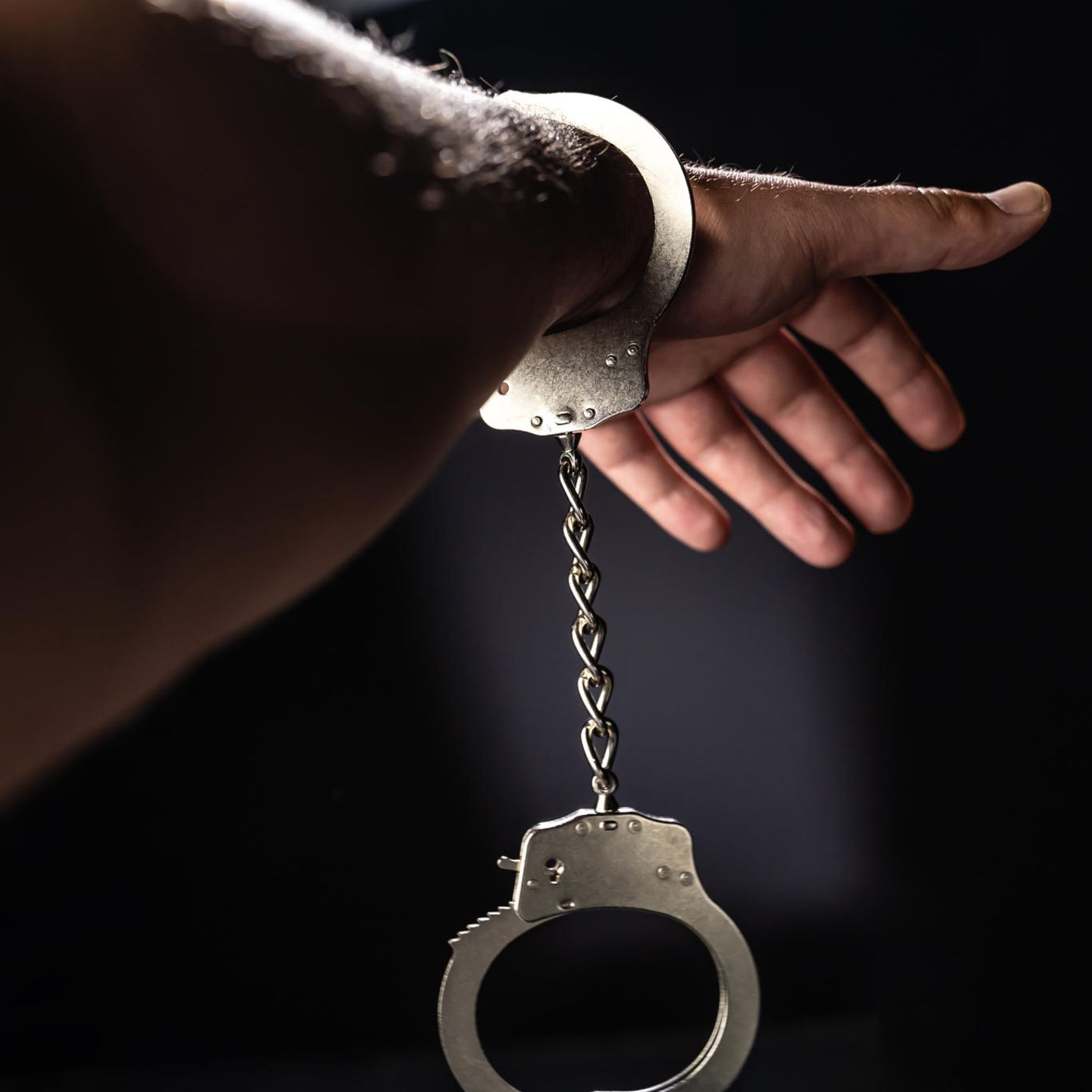 Ein Arm, an dem eine Handschelle hängt