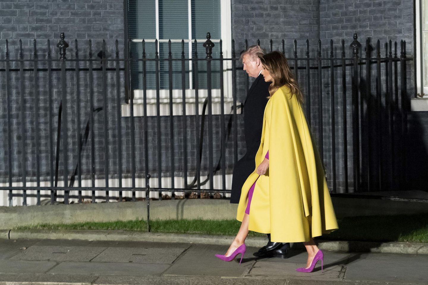 Melania Trump in gelbem Mantel und pinken Schuhen an der Seite ihres Mannes in London