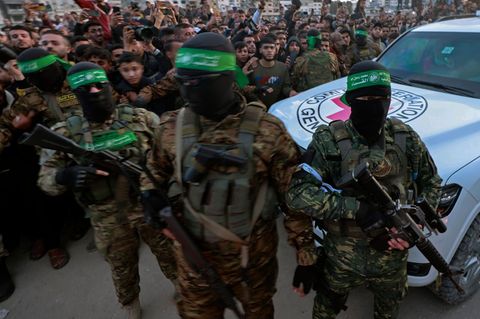 Hamas-Kämpfer eskortieren vor der ersten Übergabe ein Fahrzeug des Roten Kreuzes in Gaza-Stadt, um israelische Geiseln abzuholen