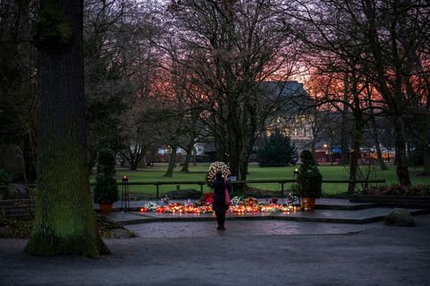 Eine Frau steht vor einer Gedenkstelle mit Grablichtern im Park Schöntal in Aschaffenburg
