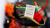Eine Demonstrantin trägt einen Karnevalshut mit einem Schild "Kunterbunt ist besser als braun"