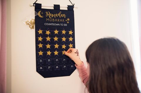 Mädchen steht vor einem Ramadan-Kalender