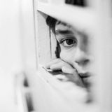 Teenager schaut aus der Tür einer Einzelhaftzelle einer Jugendstrafanstalt