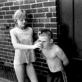 Mädchen lässt jüngeren Jungen an einer Zigarette ziehen