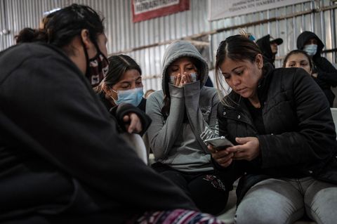Südamerikansiche Migranten verfolgen Donald Tumps Amtseinführung auf einem Handy.