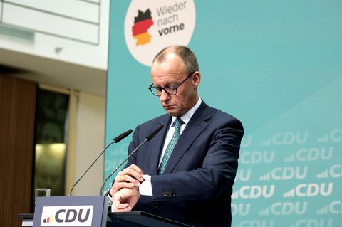 Friedrich Merz schaut bei einer Pressekonferenz auf seine Uhr.