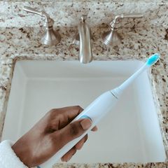 Person hält eine elektrische Zahnbürste