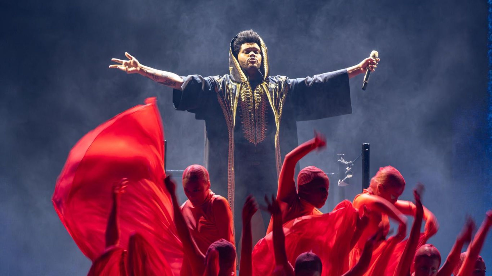 The Weeknd auf der Bühne bei einem Auftritt mit rot gekleideten Statisten