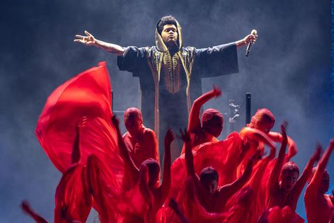The Weeknd auf der Bühne bei einem Auftritt mit rot gekleideten Statisten