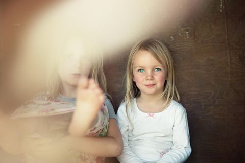 Zwei Mädchen sitzen nebeneinander, eins verschwimmt dabei in der Unschärfe – ist eins davon ein Lieblingskind?