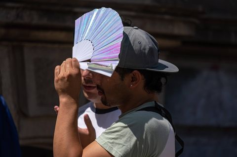 Mehr Klimatote befürchtet: Mann mit Fächer schützt sich vor der Sonne