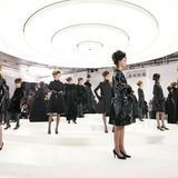 Chanel-Models in schwarzen Kleidern auf einem weißen, runden Laufsteg