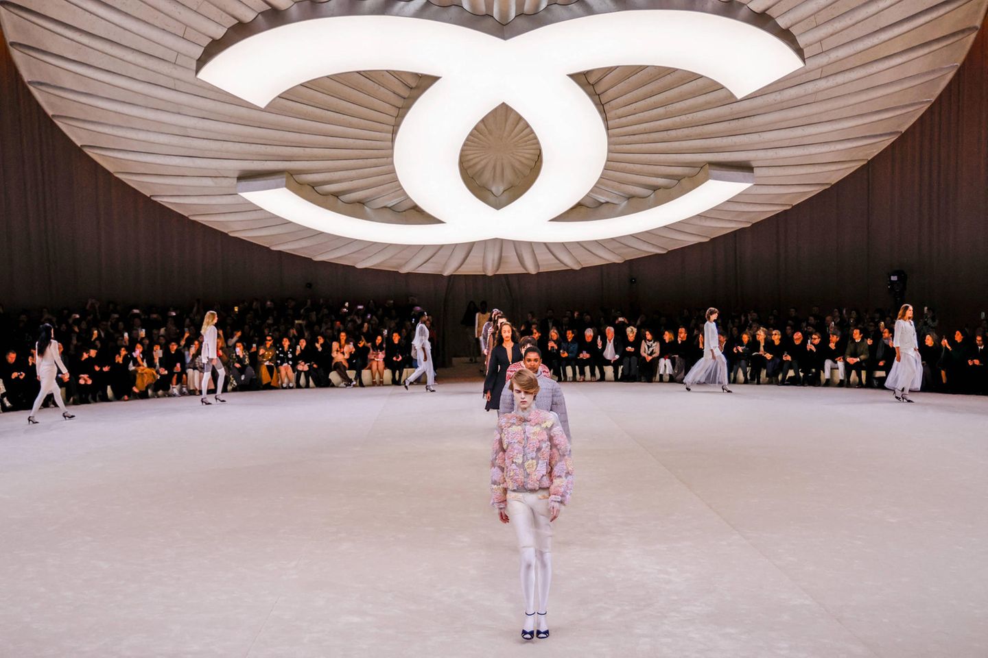 Showkulisse von Chanel mit großem Logoknopf, der über dem Laufsteg schwebt