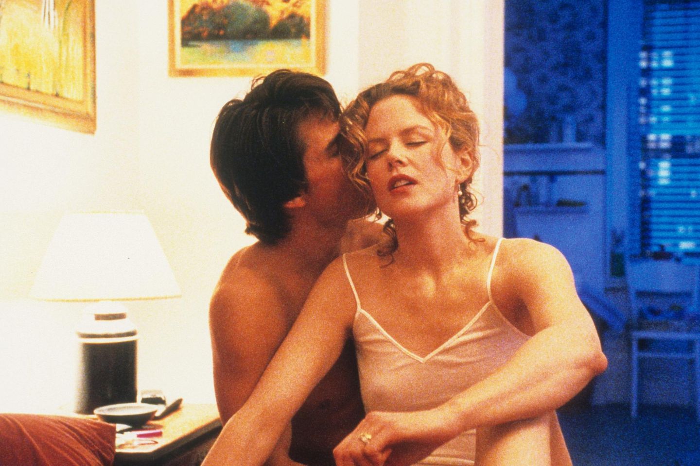 Tom Cruise umarmt Nicole Kidman von hinten und küsst ihr Ohr in einer Szene des Film "Eyes Wide Shut"