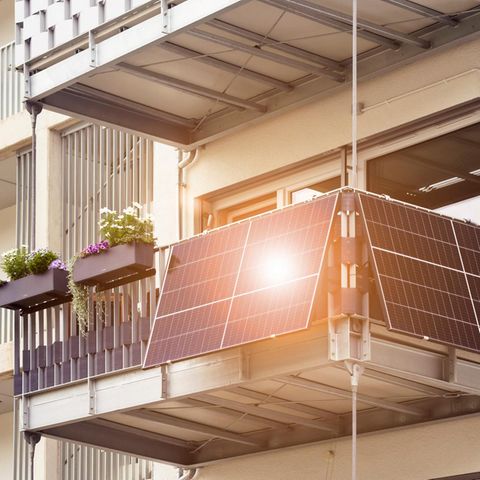 800-Watt-Grenze beim Balkonkraftwerk: Hausfassade mit Balkon, an dem vier Solarmodule angebracht sind.