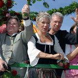 Robert Atzorn und seine Frau, die ein Dirndl trägt, winken von einem Oktoberfest-Wagen