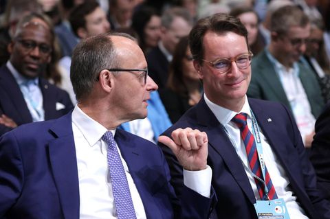 Friedrich Merz zeigt mit dem Daumen auf sich, dahinter sitzt Hendrik Wüst und lächelt