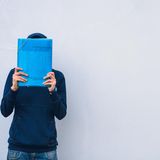 Mann verbirgt sein Gesicht hinter einer Aktenmappe