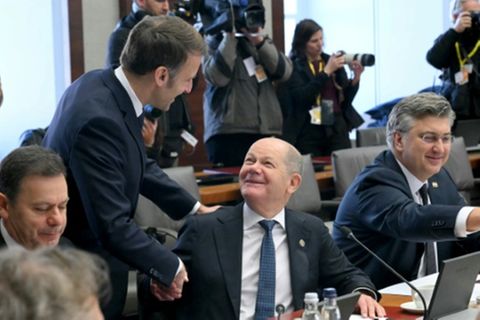 Frankreichs Präsident Macron (stehend) und Bundeskanzler Scholz