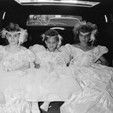 Wie kleine Prinzessinnen in Ballkleidern reihen sich diese drei Mädchen nebeneinander auf dem Rücksitz auf. Wohin sie wohl fahren?