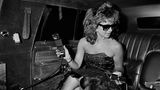 Eine Frau mit Sonnenbrille und Telefon in der Hand auf dem Rücksitz der Limousine