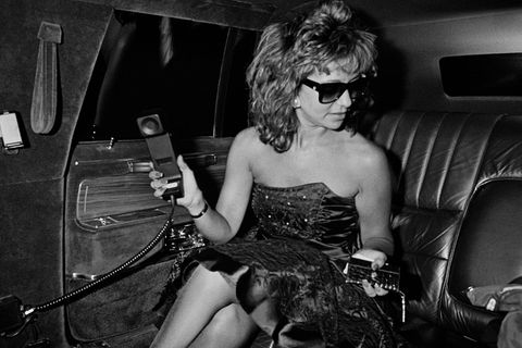 Eine Frau mit Sonnenbrille und Telefon in der Hand auf dem Rücksitz der Limousine