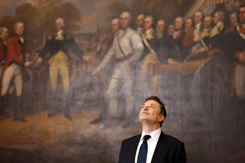 Elon Musk steht im Anzug vor einem Ölgemälde im Kapitol und blickt zur Decke