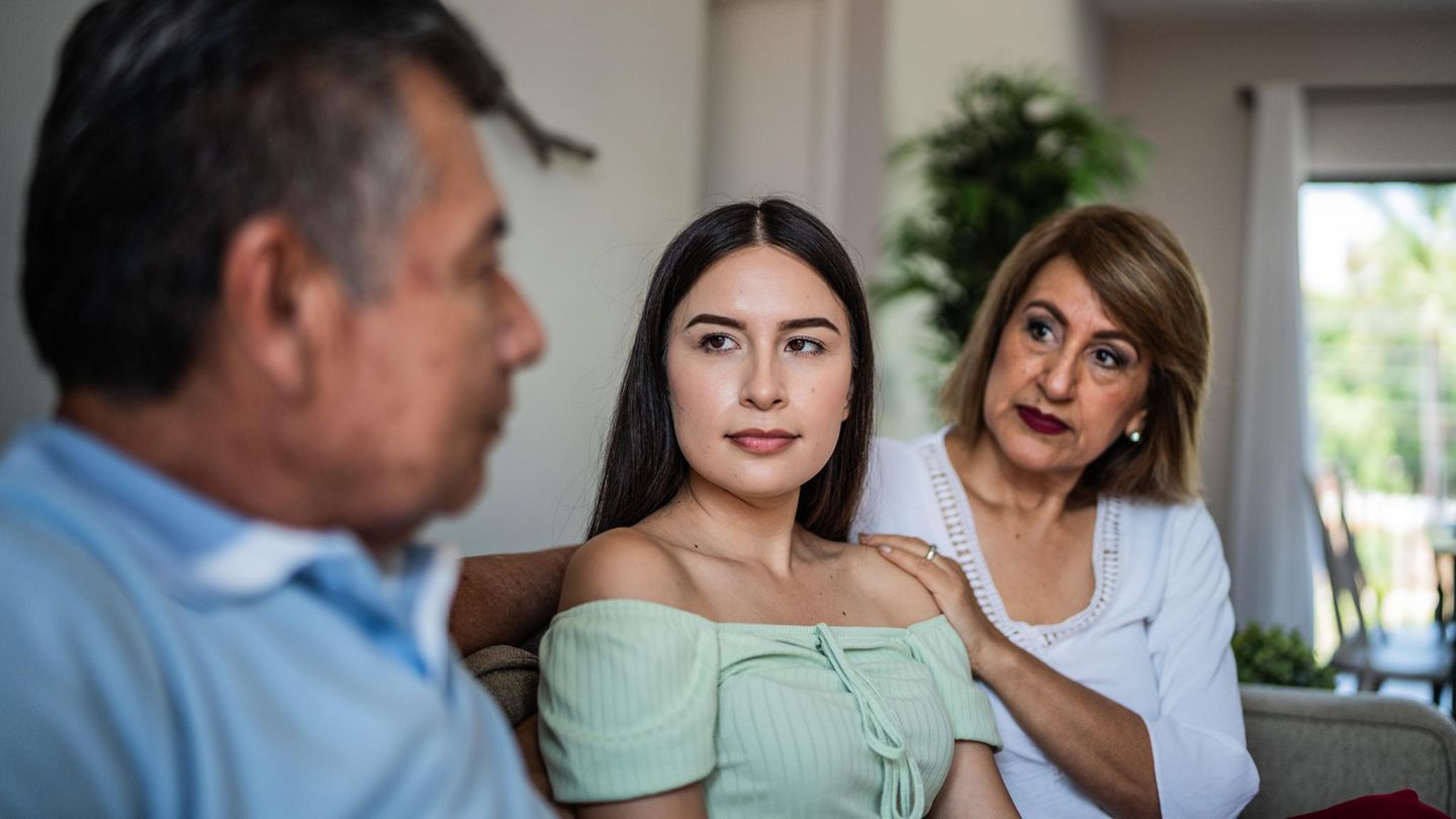 Eine junge Frau sitzt neben ihren Eltern. Hat sie Asperger?