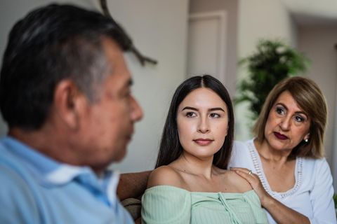 Eine junge Frau sitzt neben ihren Eltern. Hat sie Asperger?