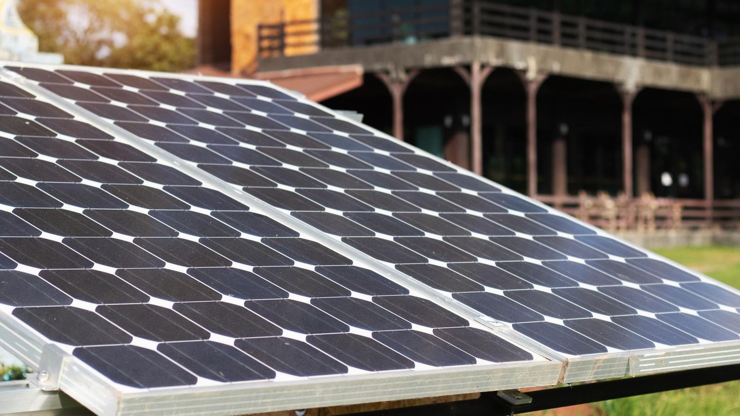 Ein Balkonkraftwerk liegt vor einem Haus auf einer Wiese.