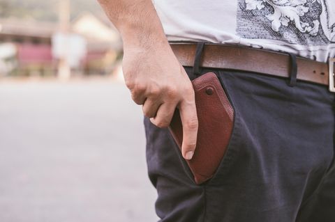 Rückansicht des Menschen halten Geldbörse in der Gesäßtasche seiner Hose chino